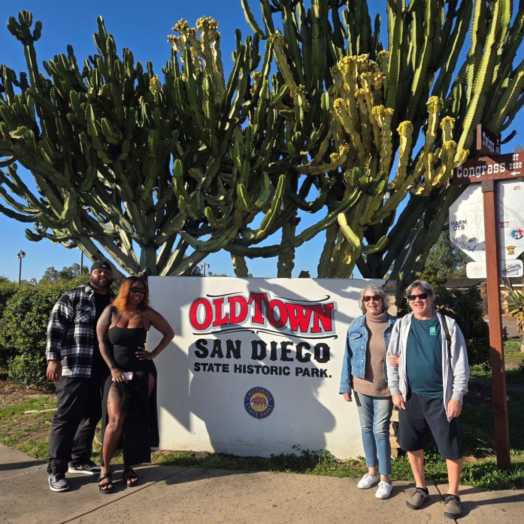 Tour guests at the Old Town San Diego State Historic Park sign